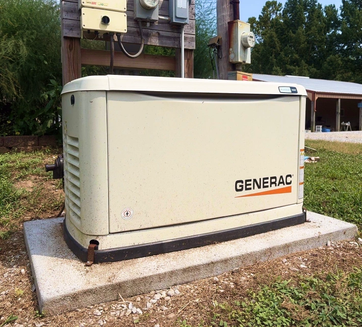 Generac standby generator installed outdoors on a concrete pad beside residential electrical service equipment